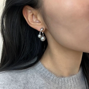 Boucles d'oreilles élégantes à double perle sur base argentée portées par un mannequin