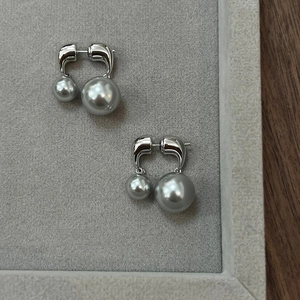Gros plan de boucles d'oreilles double perle grise avec base en métal argenté poli en U