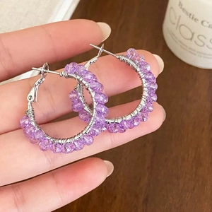 Macro detail of handmade large hoop earrings with purple faceted crystals and silver wire