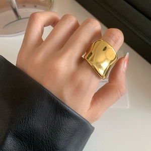 Polished minimalist gold wide asymmetric irregular ring on finger with leather sleeve