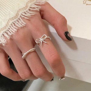 Elegant silver bow ring and double-layer pearl ring set shown on a model's hand