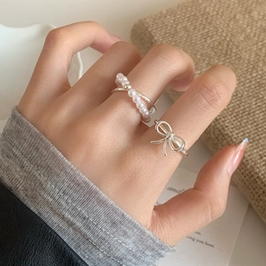 Elegant pearl layered ring with bow design shown on hand in a warm aesthetic setting