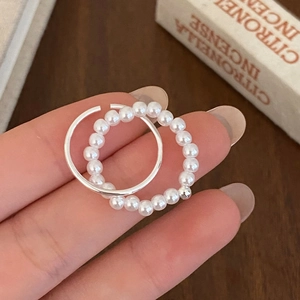 Detail of elegant two-piece ring set featuring white pearls and silver-tone bow design