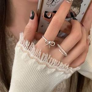 Detail view of silver bow ring and beaded double layer ring set on woman finger