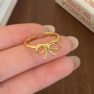 Close-up of golden bow-knot pearl ring with adjustable band on a hand