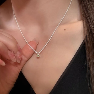 Sparkling green zircon necklace with a polished silver chain on a female collarbone