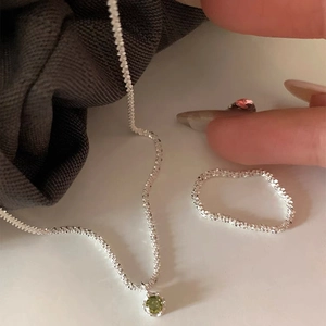 Macro view of silver necklace and ring set with sparkling green zircon pendant