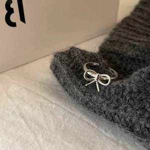 Macro view of S925 sterling silver bow ring with hallmark on grey knit background