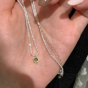 Macro detail of S925 sterling silver chain with a sparkling green zircon pendant