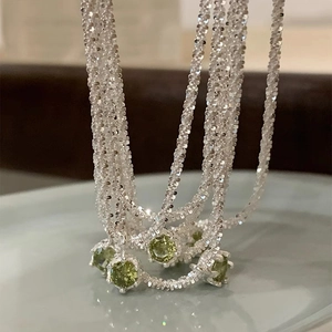 Glistening silver chain necklace featuring a round prong-set green zircon pendant