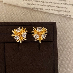 Detail of luxury firework-shaped gold stud earrings with square cubic zirconia inlay