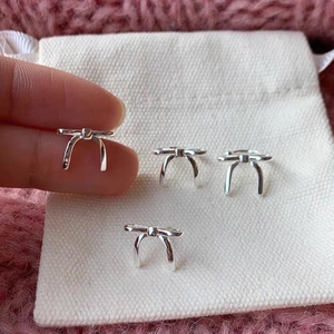 Macro shot of silver bow stud earrings on soft velvet and white cotton background