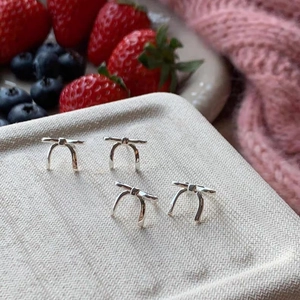 Macro view of silver bow stud earrings on a textured plate with fresh berries