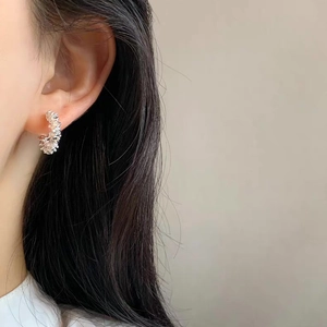 Elegant C-shaped silver earrings with crushed silver texture on a model's ear