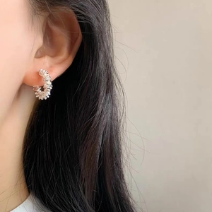 Close-up of silver C-shaped stud earring with irregular crushed texture on model ear