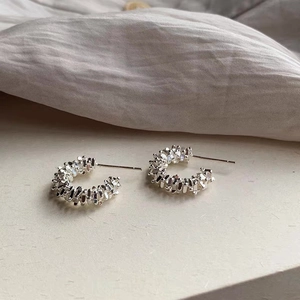 Detail of silver C-shape stud earrings with a unique textured crushed silver grain design