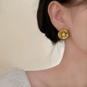 Detail of vintage gold flower pearl earrings with matte texture and white pearl center