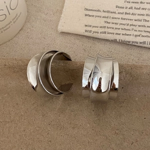 Detailed view of silver minimalist irregular multi-layer stud earrings on a brown surface