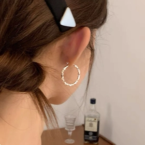 Silver twisted hoop earrings shown on model with shiny textured metallic finish