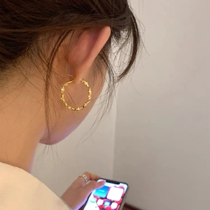 Close-up of golden round hoop earrings with textured twisted metal details for women