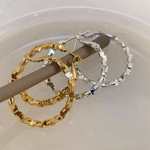 Macro shot of gold and silver geometric textured hoop earrings on a display rod