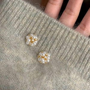 Boucles d'oreilles grappe de perles dorées avec zircons sur fond en tricot gris