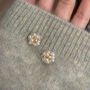 Détail de boucles d'oreilles en perles et zircons posées sur un tissu en maille douce