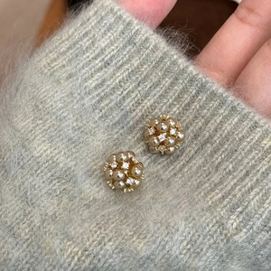Gros plan détaillé des boucles d'oreilles perles champagne et zircon sur un pull gris doux