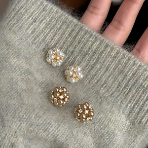 Gros plan de boucles d'oreilles en perles et strass sur un poignet de pull en maille