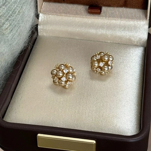 Détail macro de boucles d'oreilles élégantes en perles champagne et cristaux dans un écrin
