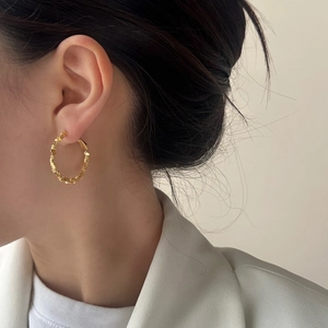 Golden irregular textured hoop earrings with a crushed silver aesthetic on model