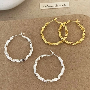 Irregular textured gold and silver hoop earrings with a faceted crushed metal finish