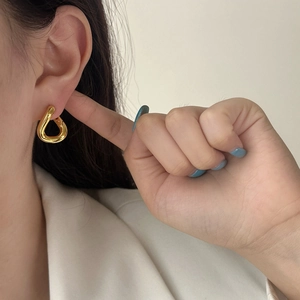 Minimalist golden teardrop earrings on model with sleek polished metallic finish