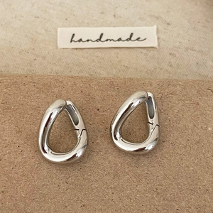 Macro detail of silver teardrop earrings with a high-polished finish on handmade label