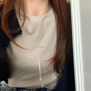 Elegant silver bow lariat necklace with long tassels shown on neck for fashion styling