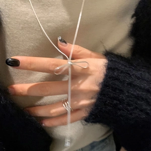 Silver bow necklace with long tassels and matching ring on model wearing black fur coat