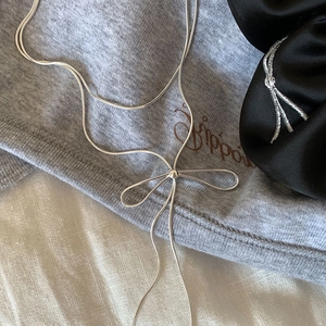 Elegant bow pendant necklace with long tassels on soft fabric background