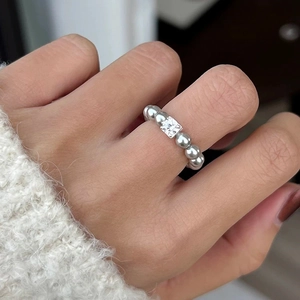 Detail of silver beaded ring featuring a square-cut zircon stone on model finger