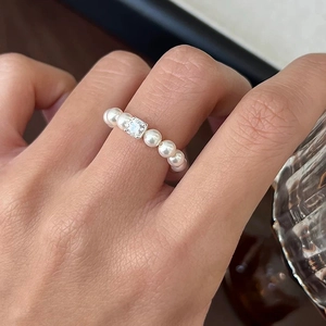 Detailed close-up of a pearl bead ring featuring a square zircon center on model hand