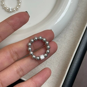 Macro detail of minimalist beaded ring with dark grey pearls and square clear zircon stone