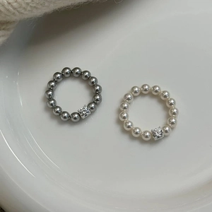 Minimalist beaded ring set with pearl and zircon detail on white ceramic display