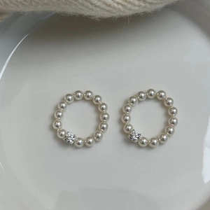 Close-up of two pearl rings with square-cut zircons on a white ceramic plate