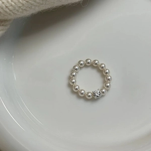 Elegant pearl bead ring with a square-cut zircon stone on a white ceramic plate
