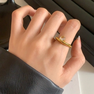 Minimalist gold textured open ring with zircon stone shown on model hand