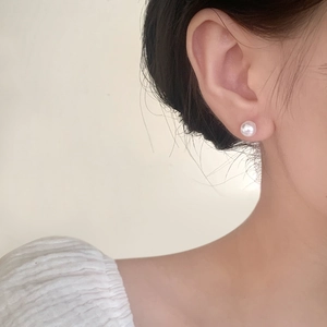Elegant white pearl stud earrings on model for a sophisticated French style aesthetic