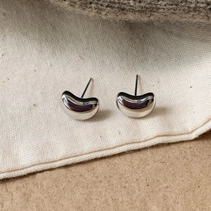 Detailed close-up of bean-shaped silver stud earrings with high-polish mirror finish