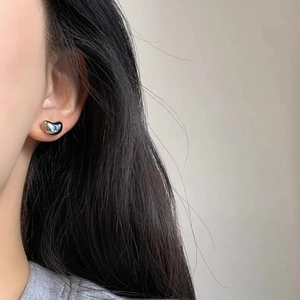 Close-up of minimalist bean-shaped silver stud earrings worn on ear for daily style
