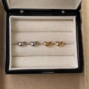 Macro view of gold and silver bean stud earrings displayed in a luxury jewelry box