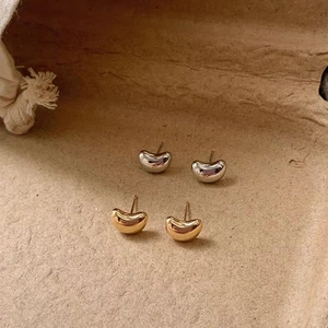 Detailed view of gold and silver bean-shaped earrings with a polished mirror finish