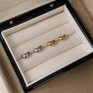 Detail of high-polished gold and silver bean earrings in a premium black leather jewelry box